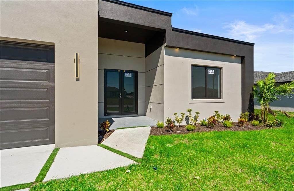 The exterior of a modern house features a garage, double front doors, and landscaping — 4105 NW 38TH TERRACE, CAPE CORAL, FL