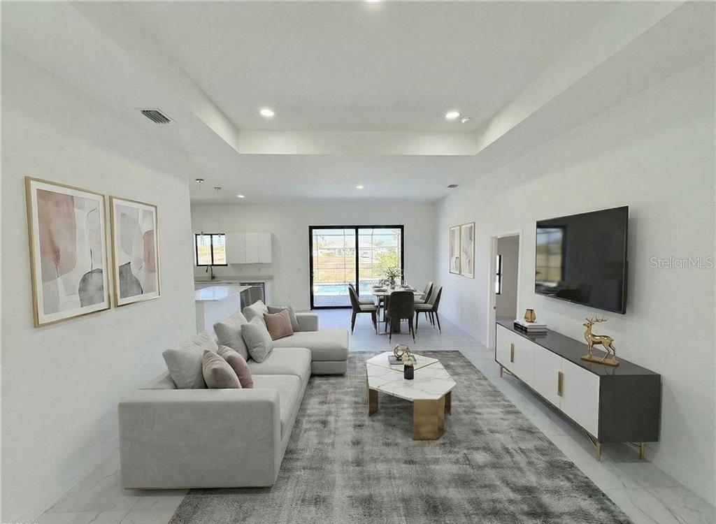 A modern open-concept living room features a sectional sofa, marble coffee table, and dining area — 4105 NW 38TH TERRACE, CAPE CORAL, FL