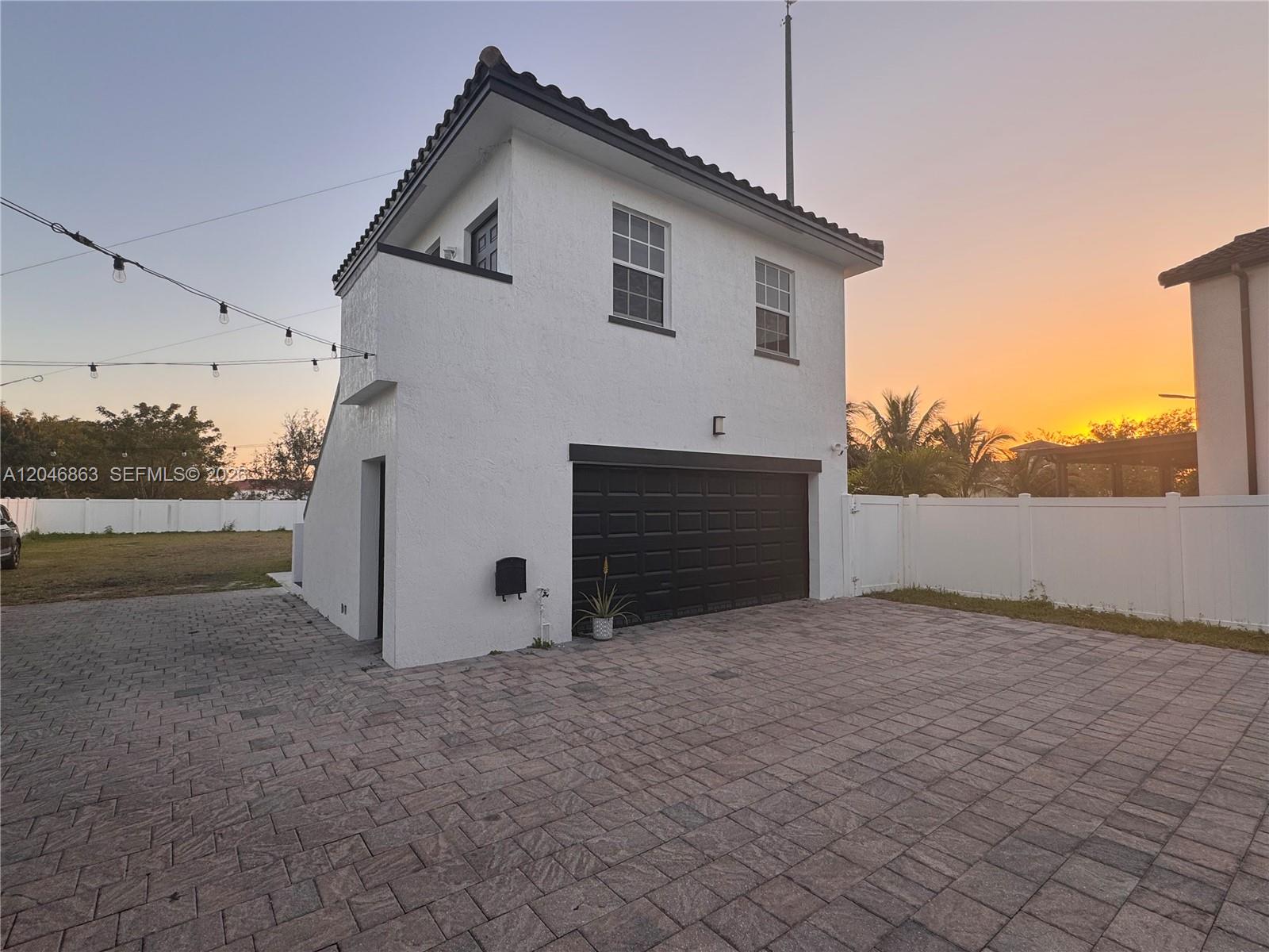 A two-story white building with a black garage door stands on a paved driveway — 16934 SW 92nd St Cir, Miami FL 33196, MIAMI, FL