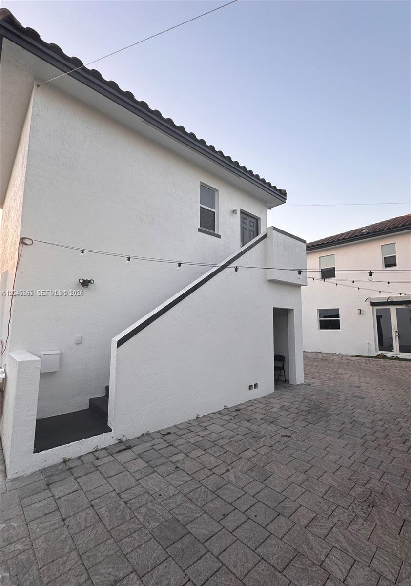An exterior view shows a white two-story building with an outdoor staircase and paved courtyard — 16934 SW 92nd St Cir, Miami FL 33196, MIAMI, FL