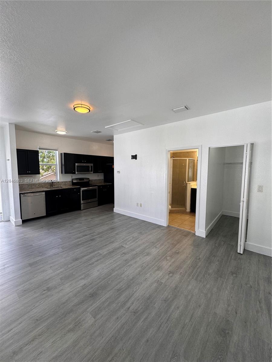 An open-concept room features a kitchen with dark cabinets and gray wood-look flooring — 16934 SW 92nd St Cir, Miami FL 33196, MIAMI, FL