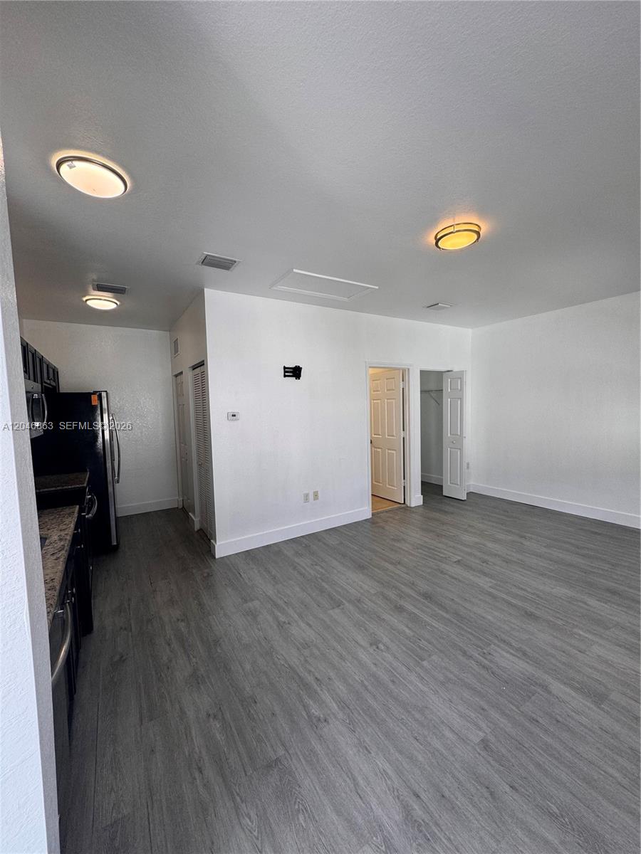 This room features gray wood-look flooring, white walls, recessed lighting, and an adjacent kitchen area — 16934 SW 92nd St Cir, Miami FL 33196, MIAMI, FL