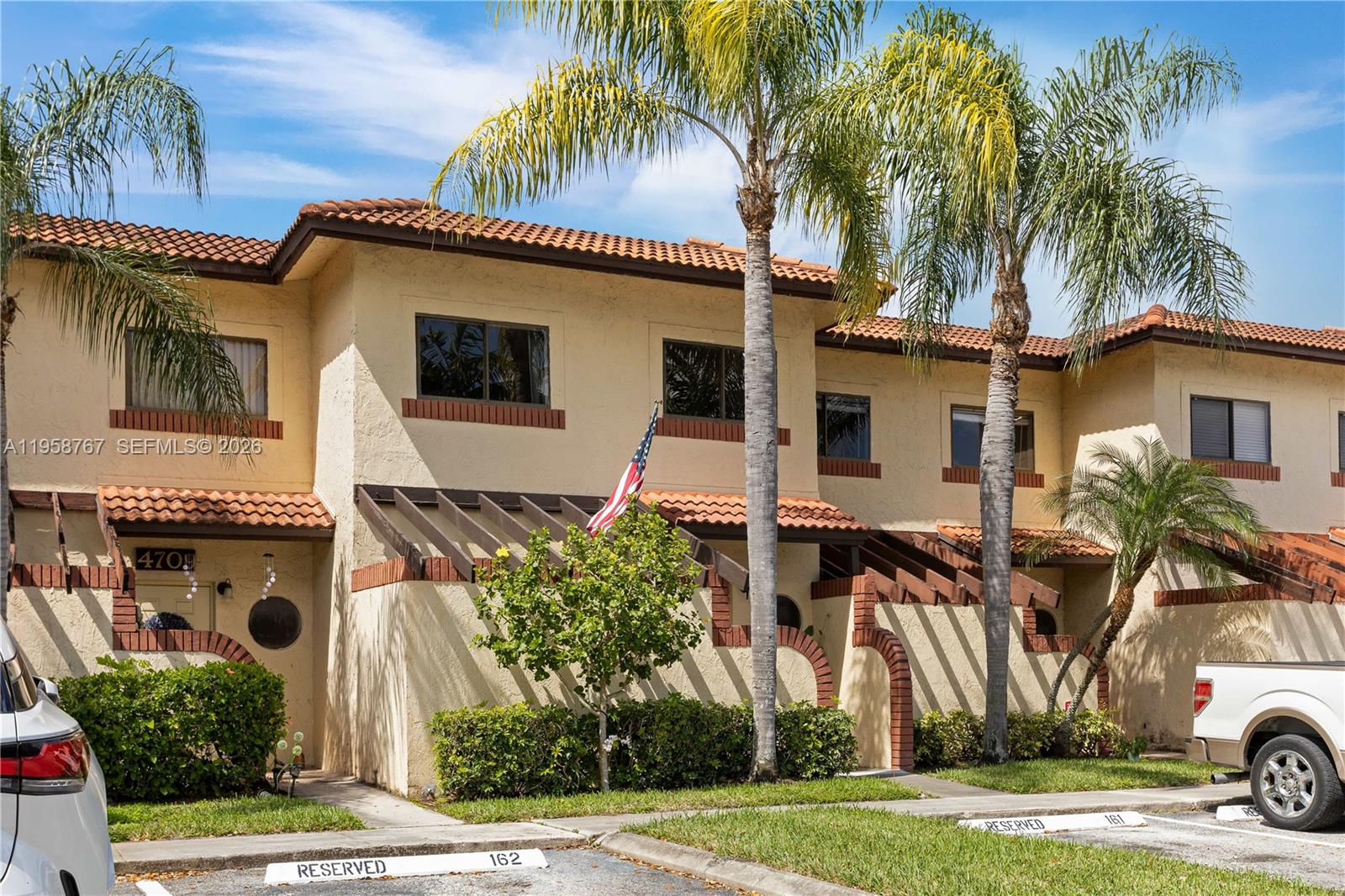 A two-story stucco townhouse features a tile roof, wooden trellises, and palm trees — 4713 N Pine Island Rd, Sunrise FL 33351, SUNRISE, FL