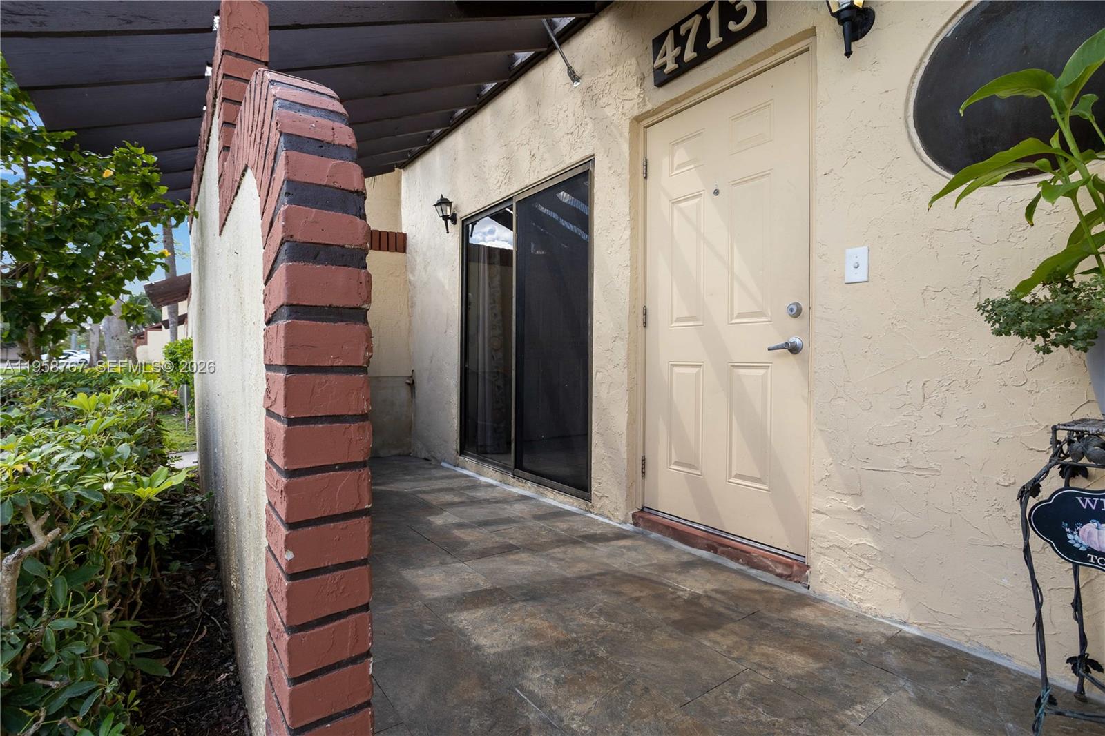 A tiled entryway features a brick archway, a sliding glass door, and a beige door — 4713 N Pine Island Rd, Sunrise FL 33351, SUNRISE, FL