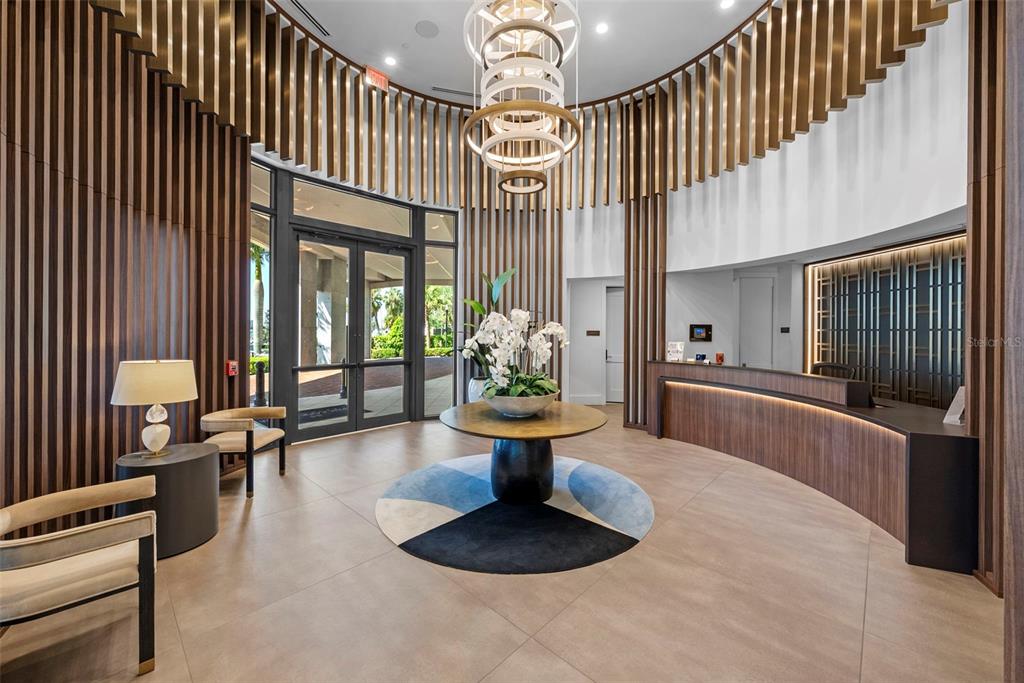 A modern kitchen features a large white island, wood-tone cabinetry, and a mirrored tile backsplash — 2103 BAYSHORE BOULEVARD UNIT 703, TAMPA, FL