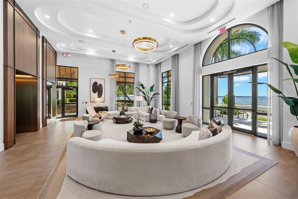 A bathroom features botanical wallpaper, a soaking tub, wood-toned vanity cabinets, and a large mirror — 2103 BAYSHORE BOULEVARD UNIT 703, TAMPA, FL