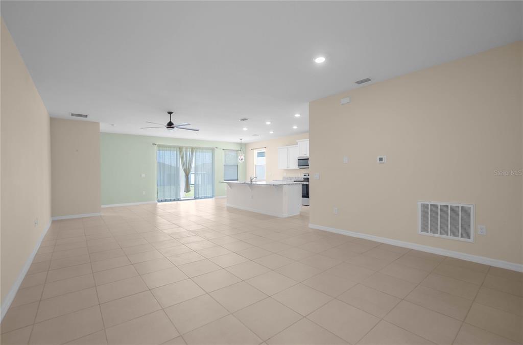 An open-concept living area features a kitchen with an island and light-colored tile flooring — 7974 PENROSE PLACE, WILDWOOD, FL