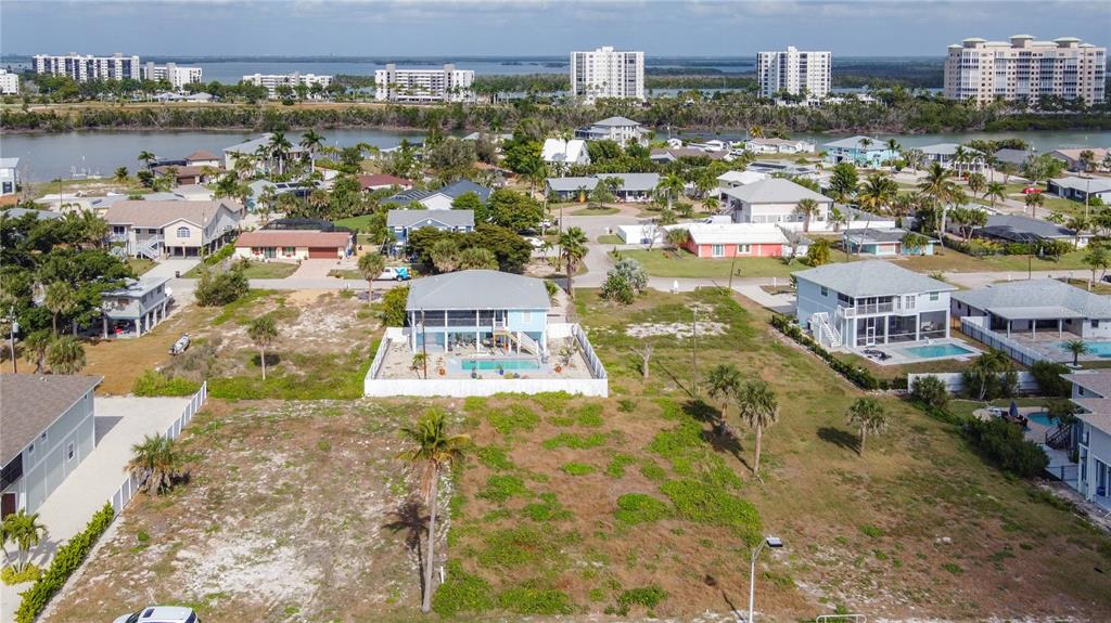 An aerial view shows a vacant lot in the foreground with a house and pool behind — 8033 ESTERO BOULEVARD, FORT MYERS BEACH, FL