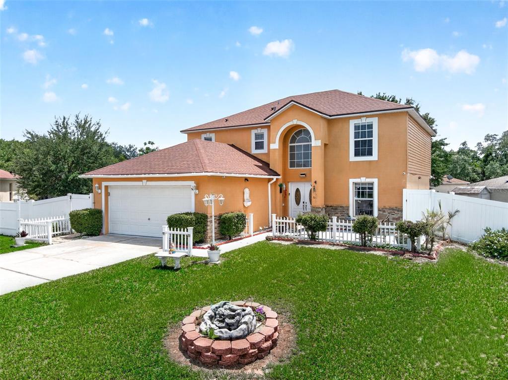 A two-story orange stucco house with a two-car garage and a front yard fountain — 1502 FORT MEADE PLACE, POINCIANA, FL