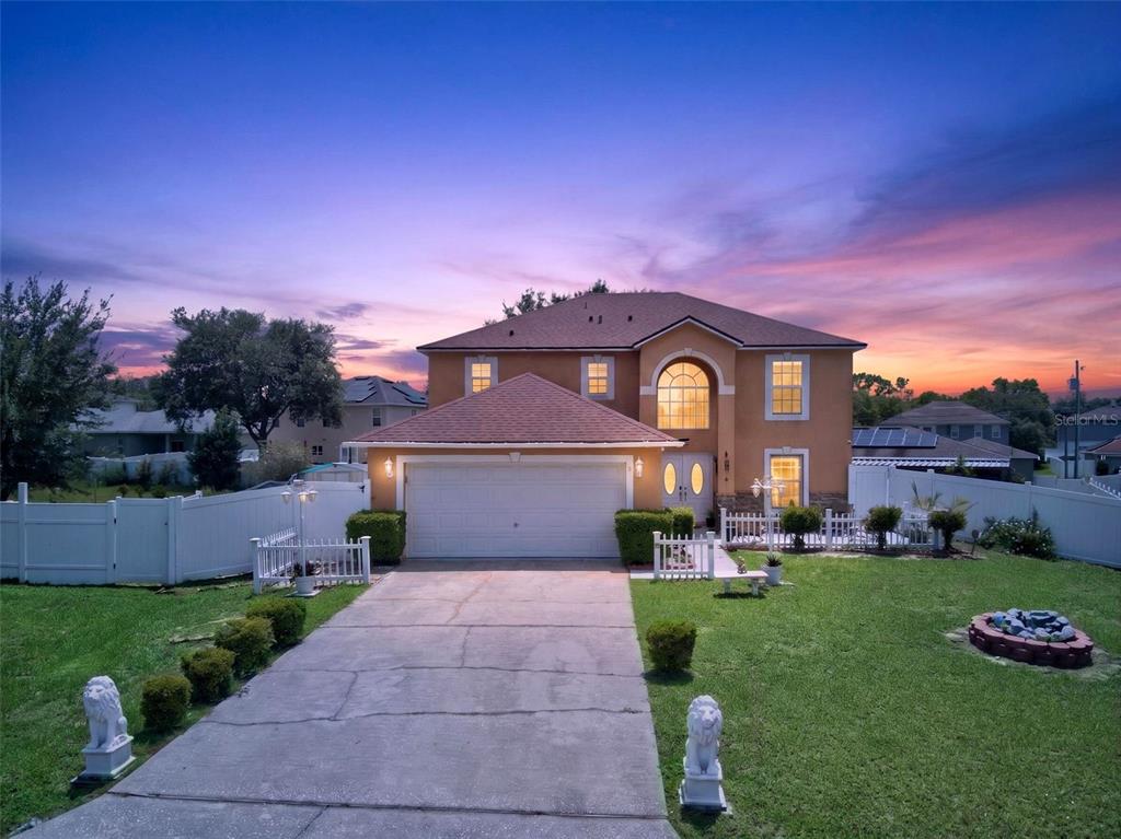 A two-story suburban house with a tan stucco exterior, a two-car garage, and a driveway — 1502 FORT MEADE PLACE, POINCIANA, FL