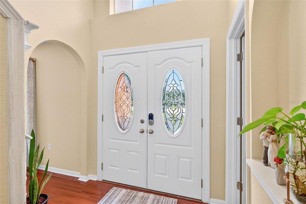 A white double front door with decorative glass inserts is set in a peach-colored wall — 1502 FORT MEADE PLACE, POINCIANA, FL