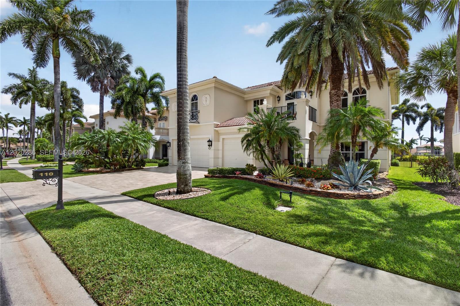 A two-story beige house with a tile roof, palm trees, and a paved driveway — 110 Abondance Dr, Palm Beach Gardens FL 33410, PALM BEACH GARDENS, FL