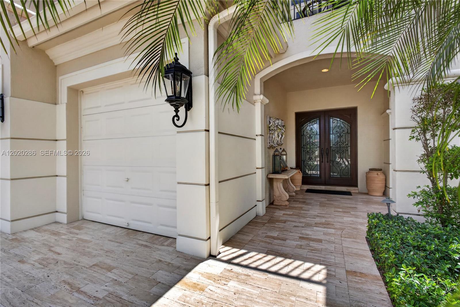 A beige stucco home exterior features a white garage door, arched entryway, and stone flooring — 110 Abondance Dr, Palm Beach Gardens FL 33410, PALM BEACH GARDENS, FL