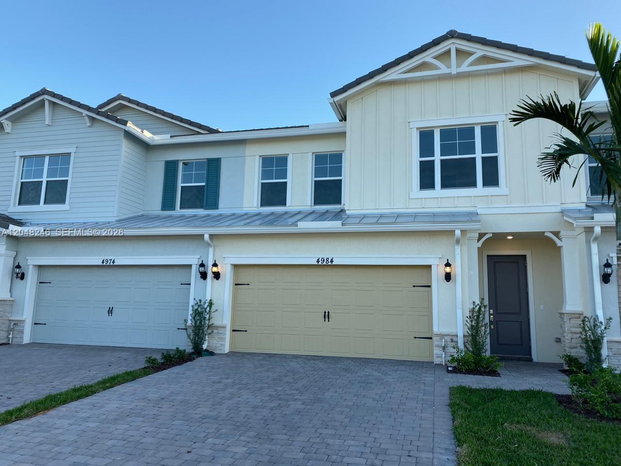 A two-story townhouse exterior features a paved driveway, two garage doors, and light-colored siding — 4984 Greenway Dr, Hollywood FL 33021, HOLLYWOOD, FL