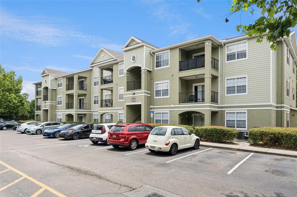 A three-story apartment building with a parking lot in the foreground — 8136 CLAIRE ANN DRIVE UNIT 207, ORLANDO, FL