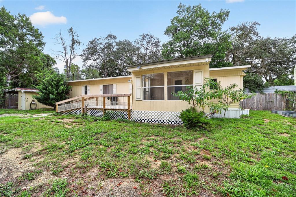A yellow mobile home features a screened-in porch, a wooden deck, and a wheelchair ramp — 15367 NE 160TH AVENUE ROAD, FORT MC COY, FL