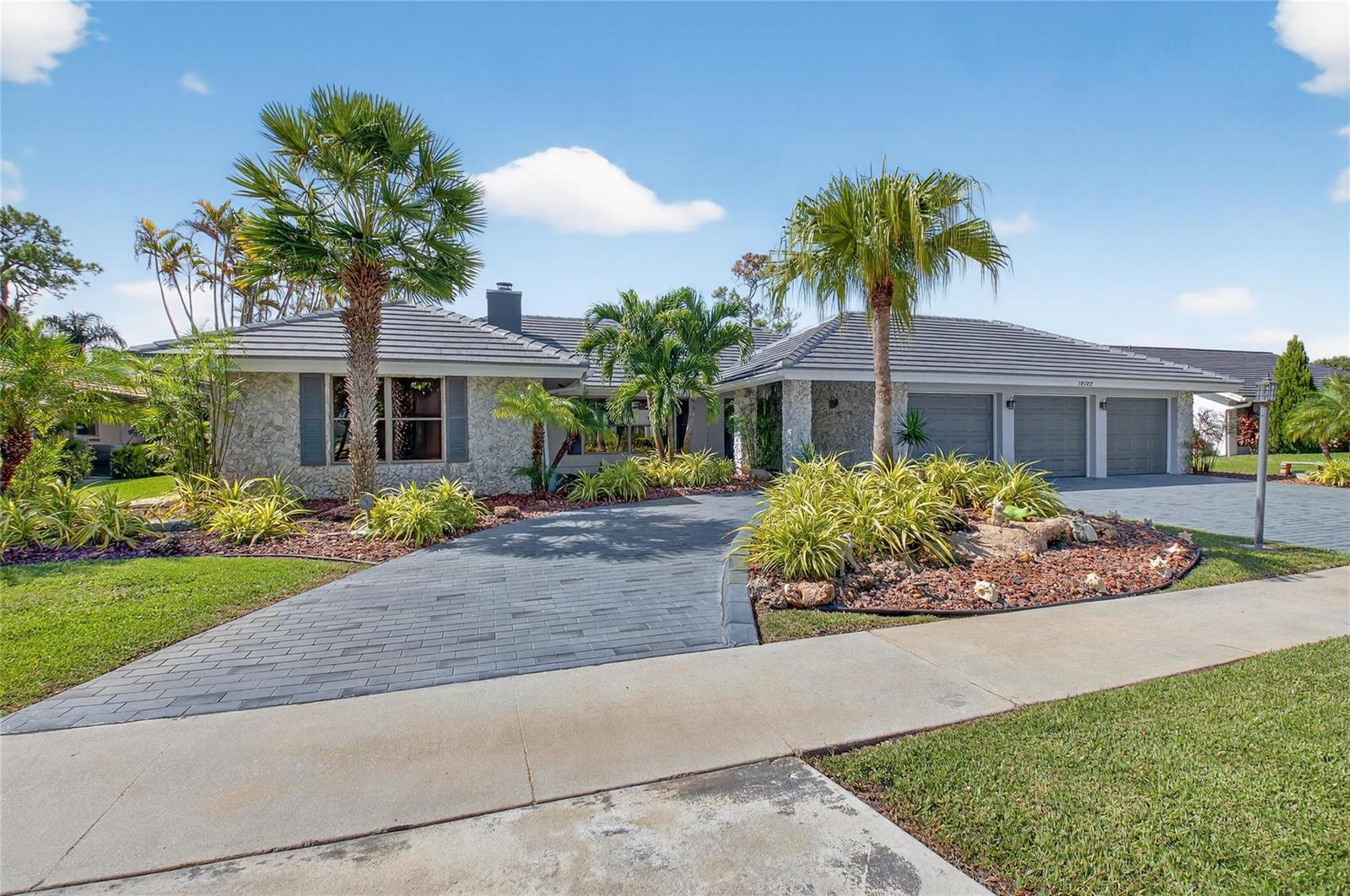 A single-story house with a stone facade, gray tile roof, and a paved driveway — 10182 Boca Woods Lane, Boca Raton FL 33428, BOCA RATON, FL