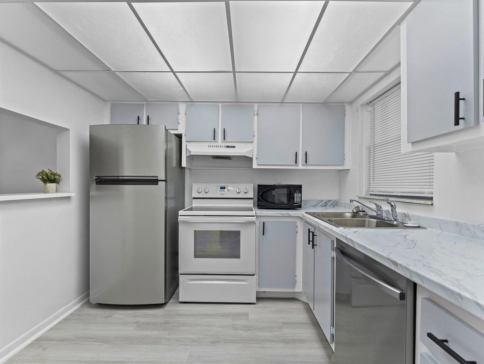 A kitchen features stainless steel appliances, white cabinets, marble-look countertops, and a drop ceiling — 6800 Royal Palm Boulevard # 207f, Margate FL 33063, MARGATE, FL