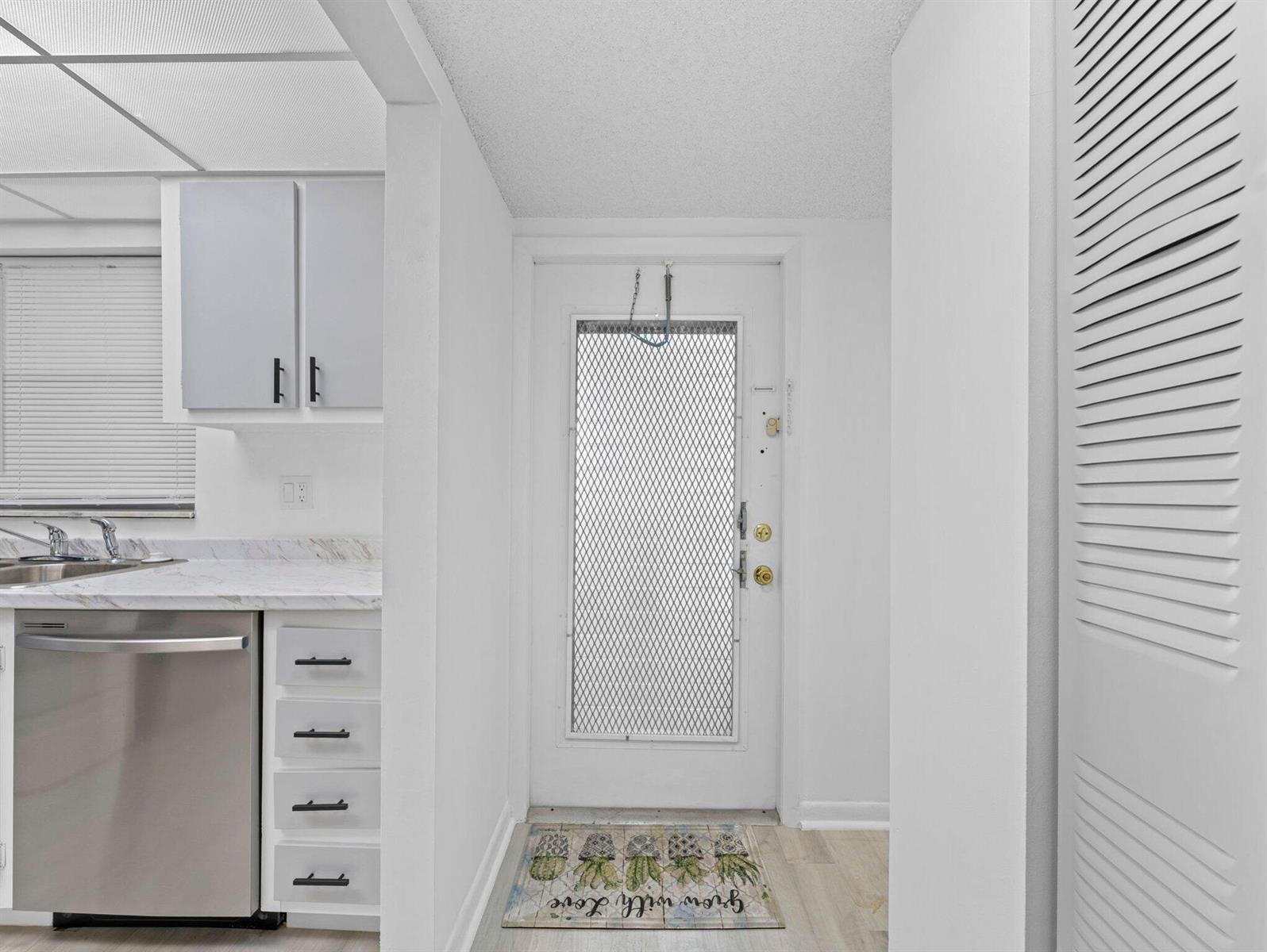 A kitchen area features white cabinets, a stainless steel dishwasher, and a door with a screen — 6800 Royal Palm Boulevard # 207f, Margate FL 33063, MARGATE, FL