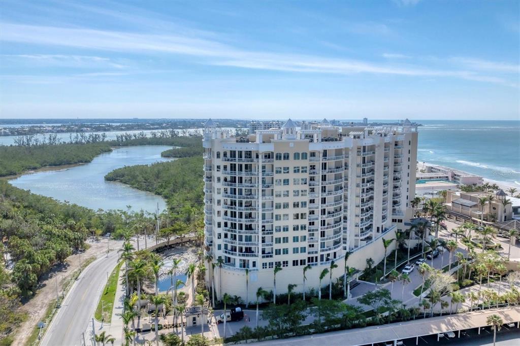 An aerial view of a tall, multi-story residential building situated between a lagoon and ocean — 1300 BENJAMIN FRANKLIN DRIVE UNIT 304, SARASOTA, FL