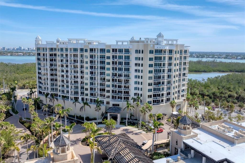 An aerial view of a multi-story residential building surrounded by palm trees and water — 1300 BENJAMIN FRANKLIN DRIVE UNIT 304, SARASOTA, FL