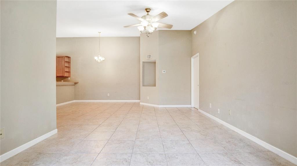 A spacious room with light-colored tile flooring, a ceiling fan, and a recessed wall niche — 6019 SCOTCHWOOD GLEN UNIT 204, ORLANDO, FL