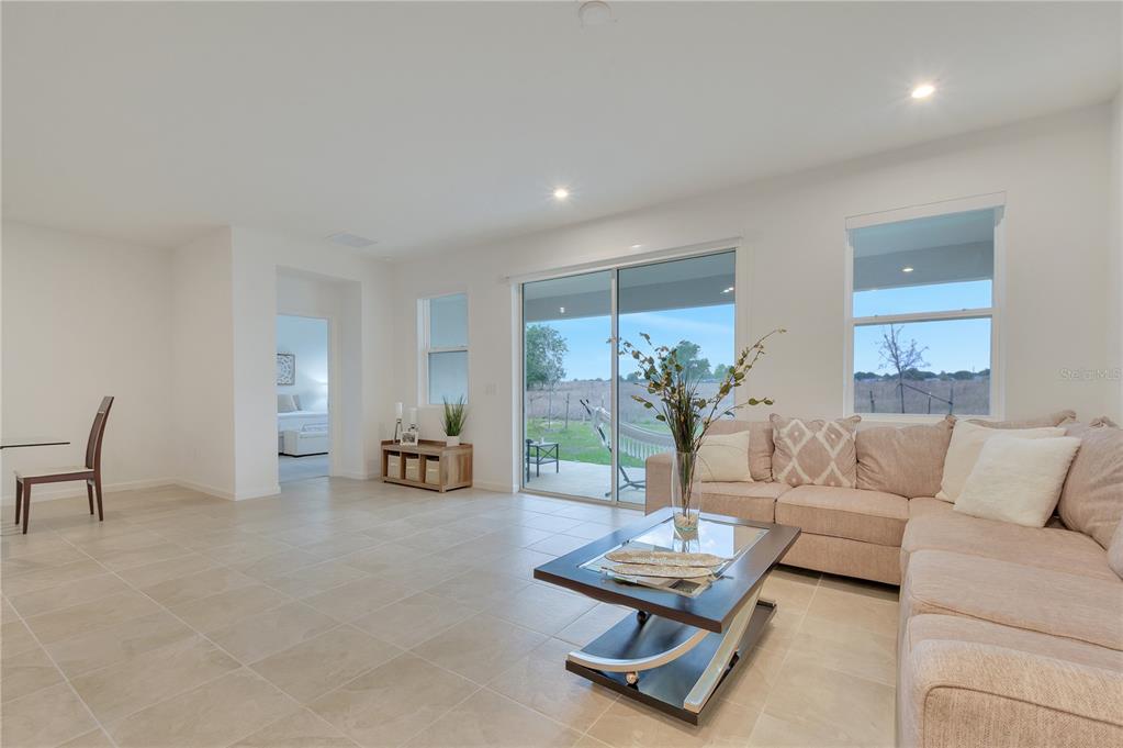 A living room features light tile flooring, a beige sectional sofa, and a sliding glass door — 1098 BOARDWALK PLACE, KISSIMMEE, FL