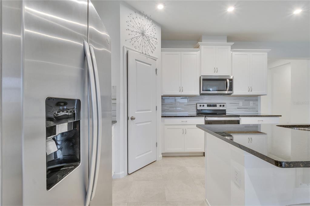 A kitchen features white cabinets, stainless steel appliances, a kitchen island, and tile flooring — 1098 BOARDWALK PLACE, KISSIMMEE, FL