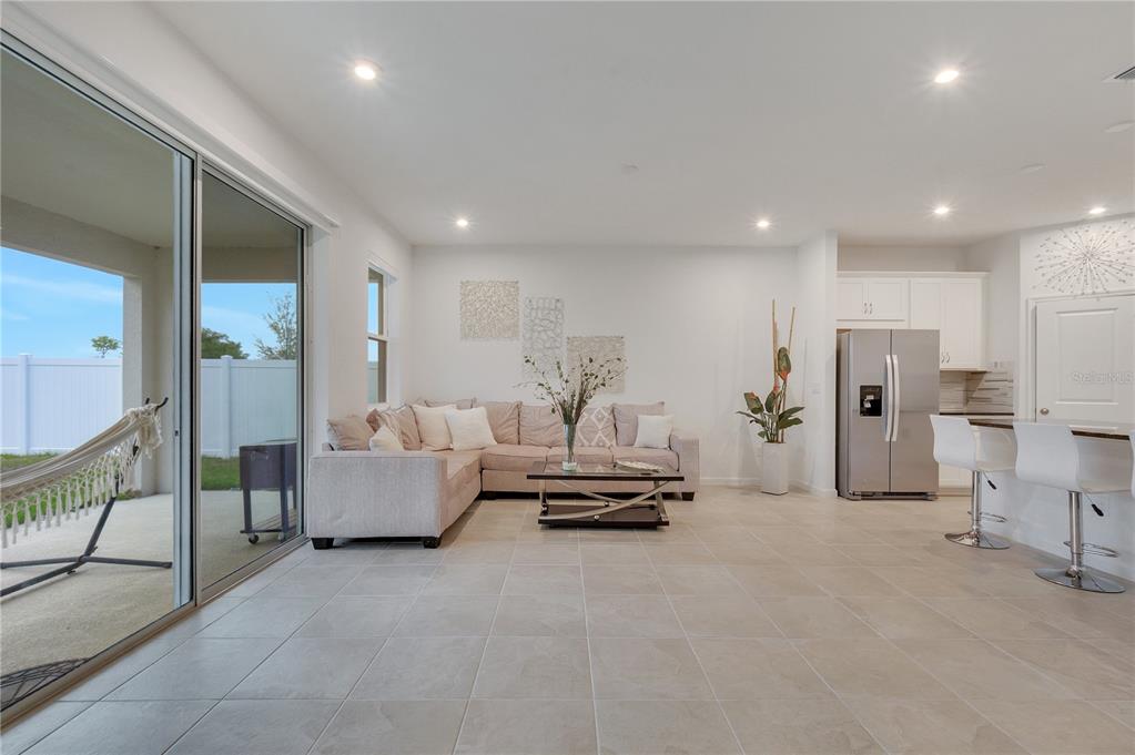A living room with tile floors, a sectional sofa, and an open kitchen with stainless appliances — 1098 BOARDWALK PLACE, KISSIMMEE, FL