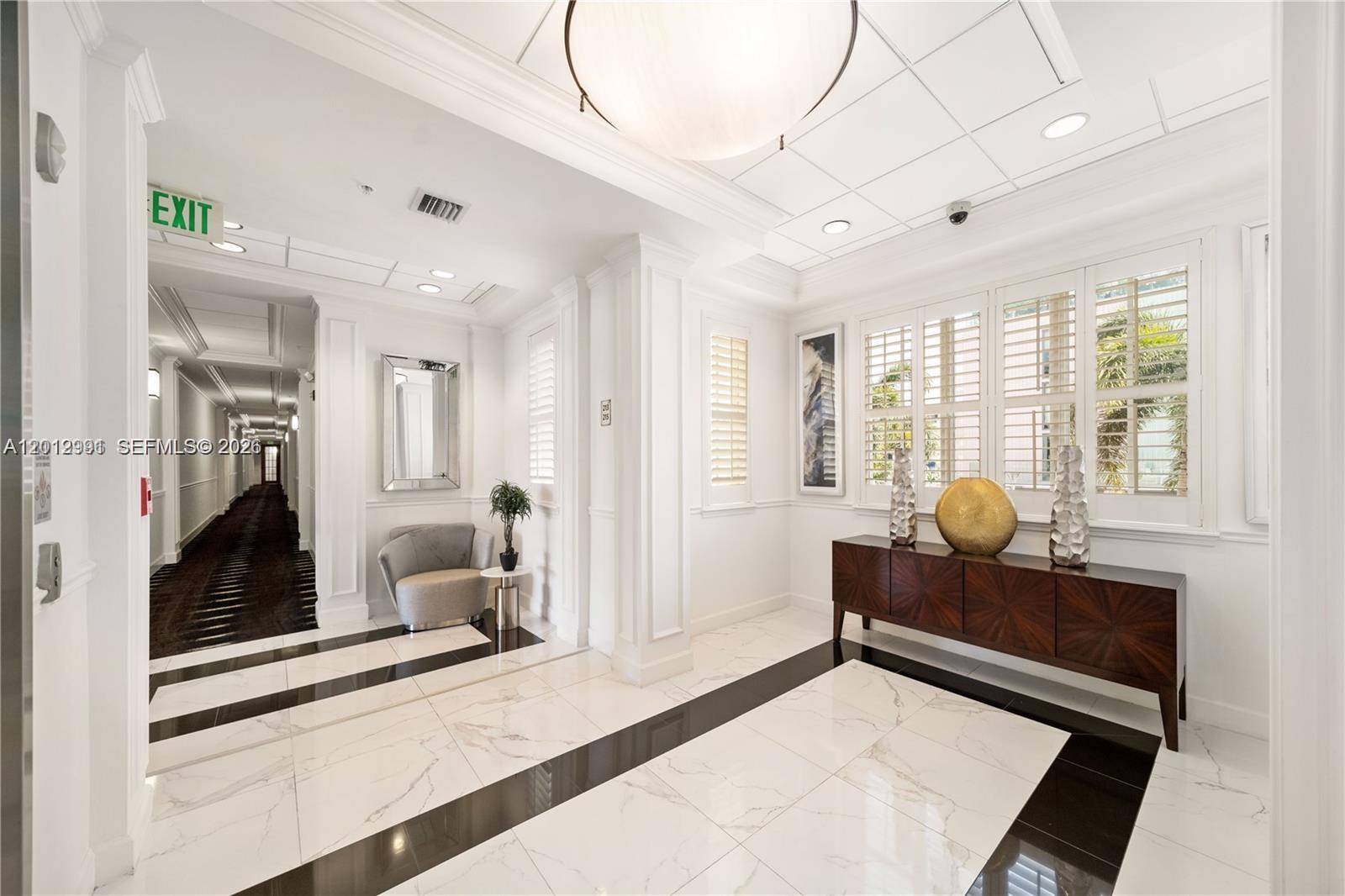 A bright, modern lobby features white marble floors with black accents, a dark wood console, and a hallway — 200 NE 2nd Ave # 304, Delray Beach FL 33444, DELRAY BEACH, FL