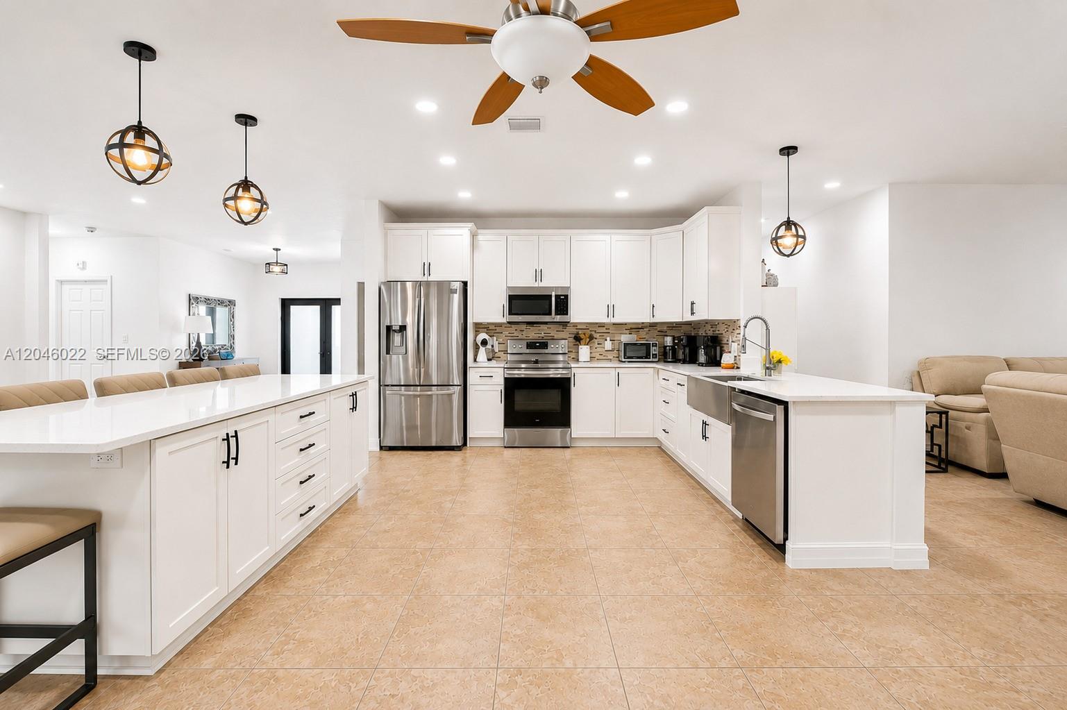 A modern kitchen features white cabinetry, stainless steel appliances, and a large central island — 26363 SW 152nd Ave, Homestead FL 33032, HOMESTEAD, FL