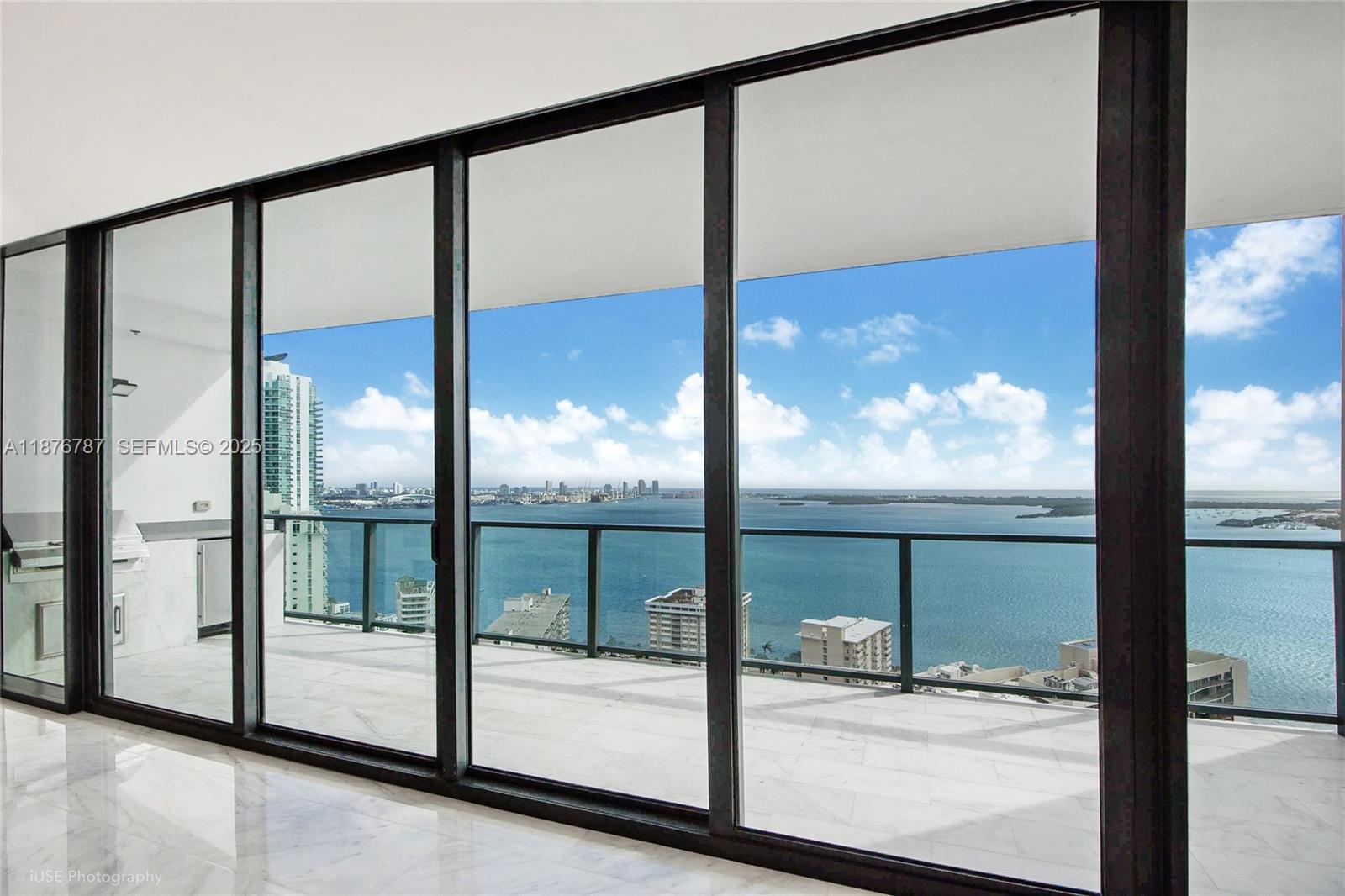 A room with floor-to-ceiling glass doors opens onto a balcony overlooking a bay — 1451 Brickell Ave # 3102, Miami FL 33131, MIAMI, FL