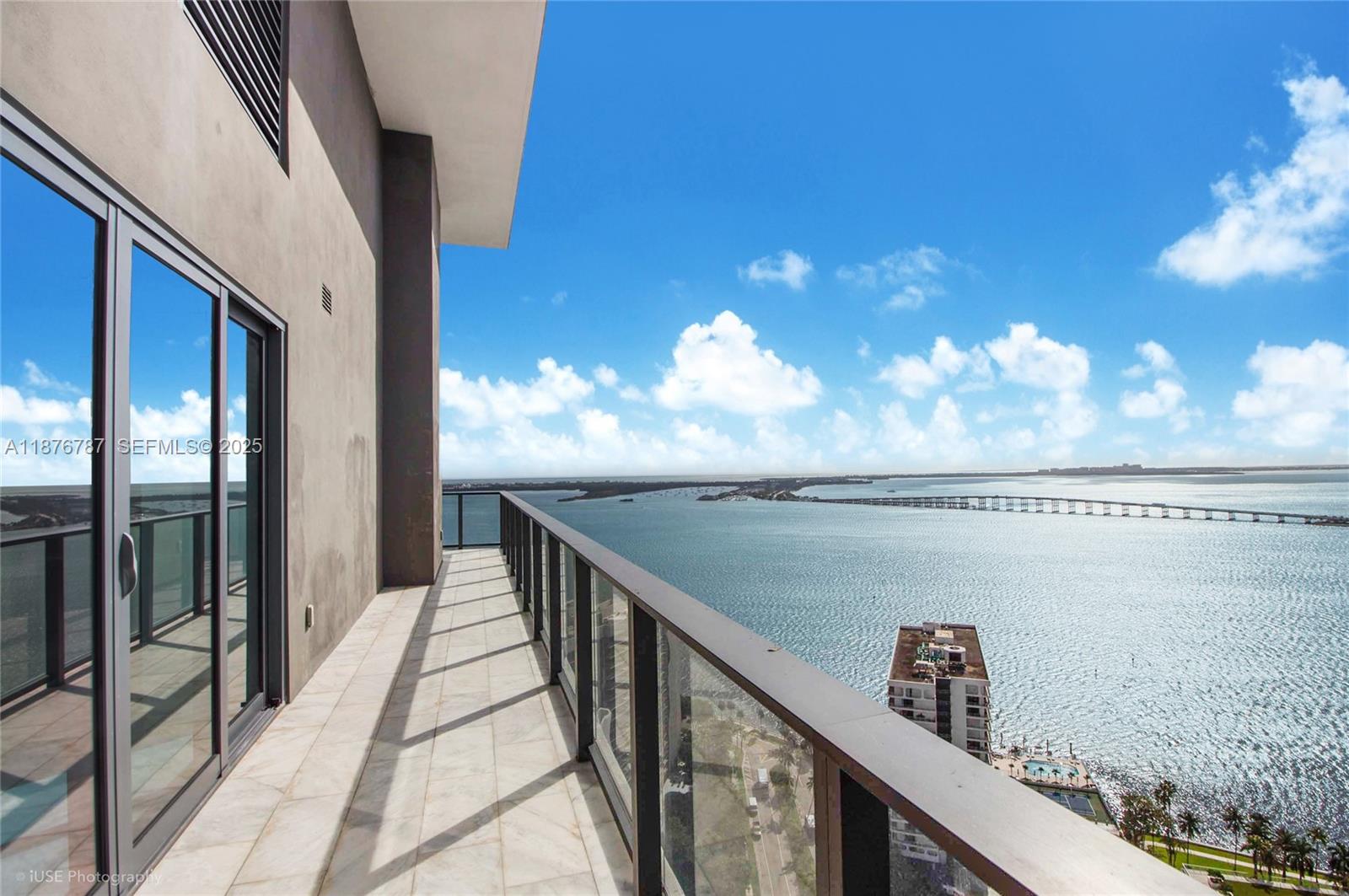 A high-rise balcony with a glass railing overlooks a bay and a distant bridge — 1451 Brickell Ave # 3102, Miami FL 33131, MIAMI, FL