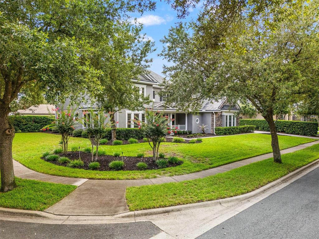 A two-story gray house with a front porch sits on a corner lot with landscaping — 25622 HAWKS RUN LANE, SORRENTO, FL
