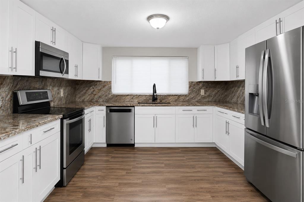 A kitchen with white cabinets, stainless steel appliances, and brown granite countertops — 1205 E SENECA AVENUE, TAMPA, FL