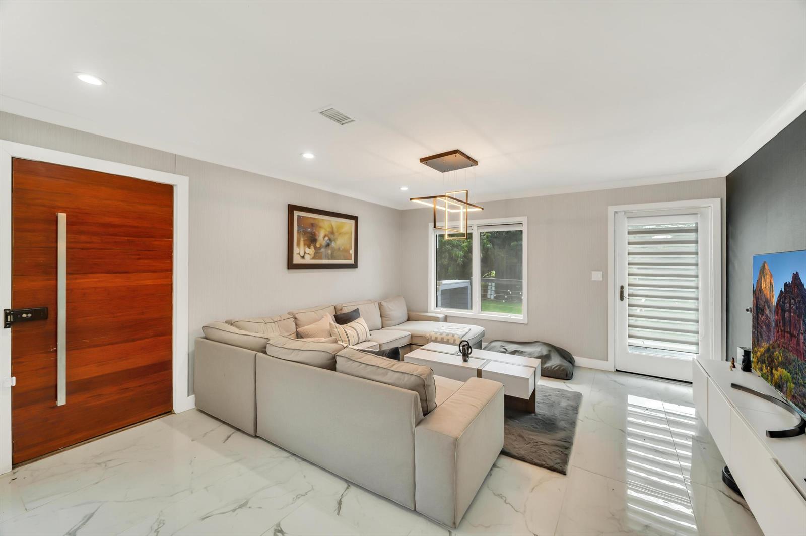 A living room features a sectional sofa, white tile floors, and a modern light fixture — 6320 86th Lane, Vero Beach FL 32967, VERO BEACH, FL