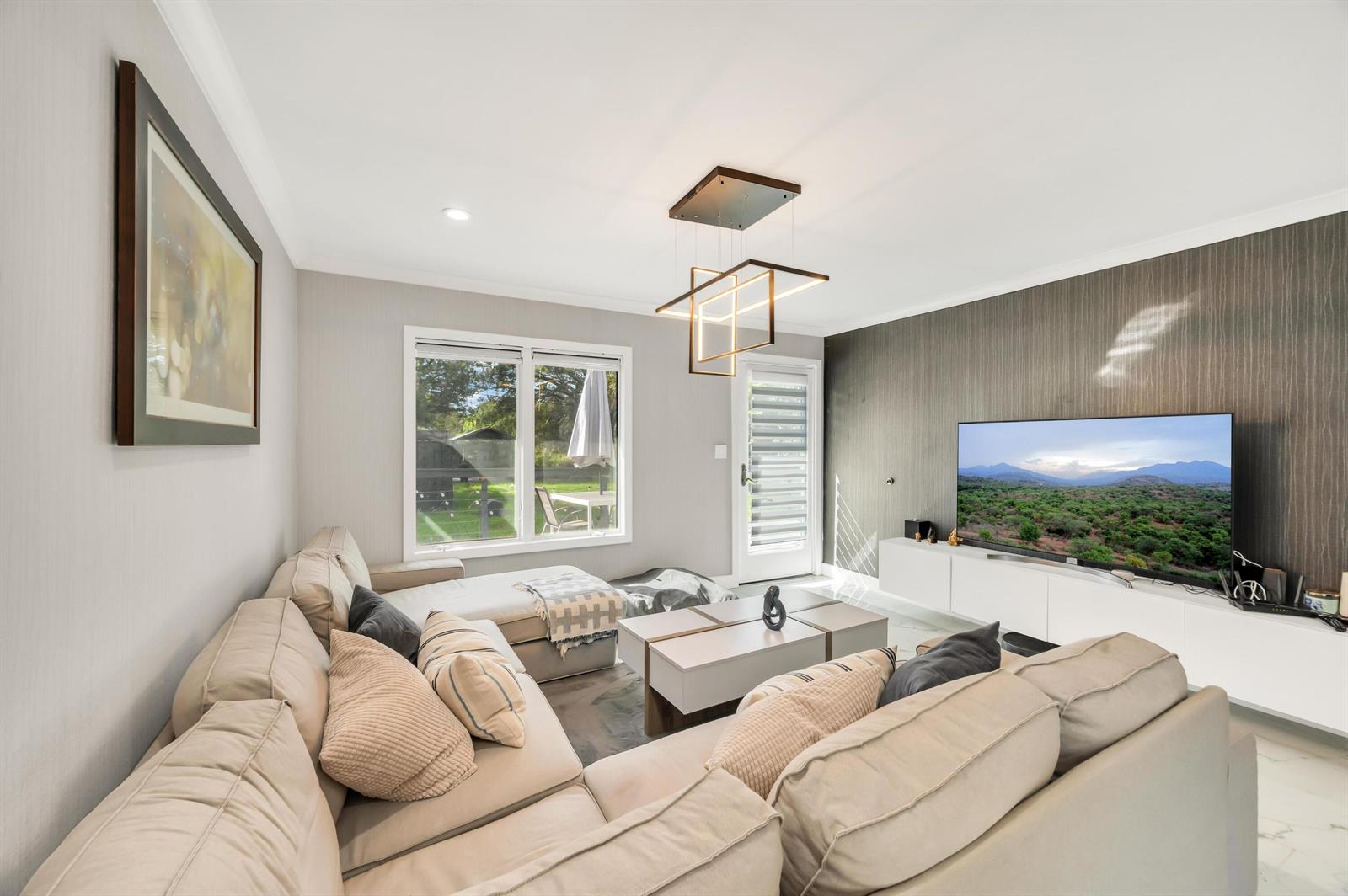 A living room features a large sectional sofa, a modern light fixture, and a television — 6320 86th Lane, Vero Beach FL 32967, VERO BEACH, FL