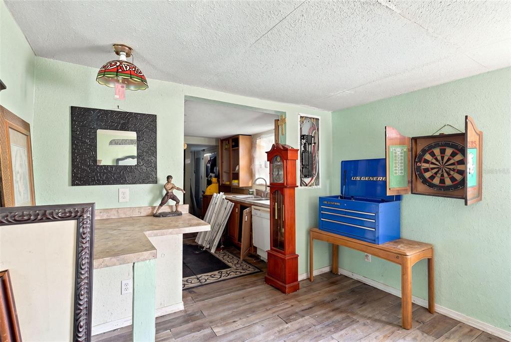 A room with light green walls, a grandfather clock, a dartboard, and a tool chest — 2221 GRANBY STREET, SANFORD, FL