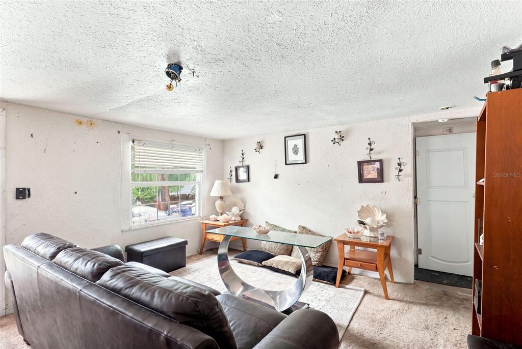 A living room features a leather sofa, a glass coffee table, and textured white walls — 2221 GRANBY STREET, SANFORD, FL