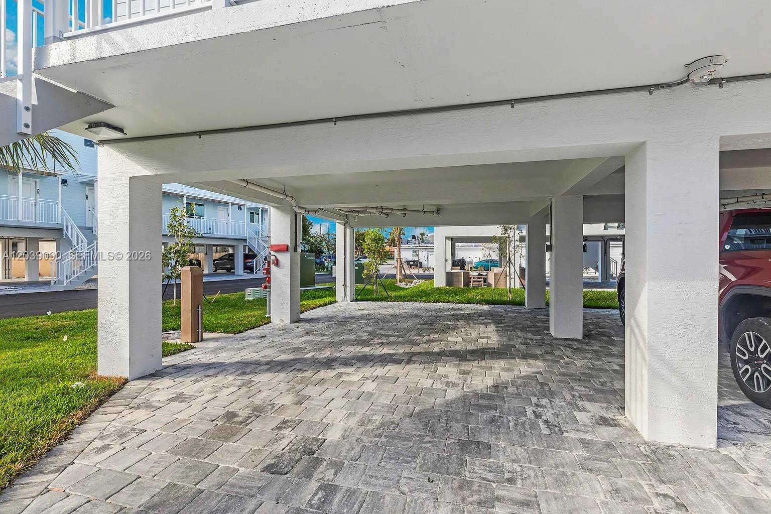 A covered parking area features gray stone pavers beneath a white elevated residential building — 10877 Overseas Hwy # 37, Marathon FL 33050, MARATHON, FL