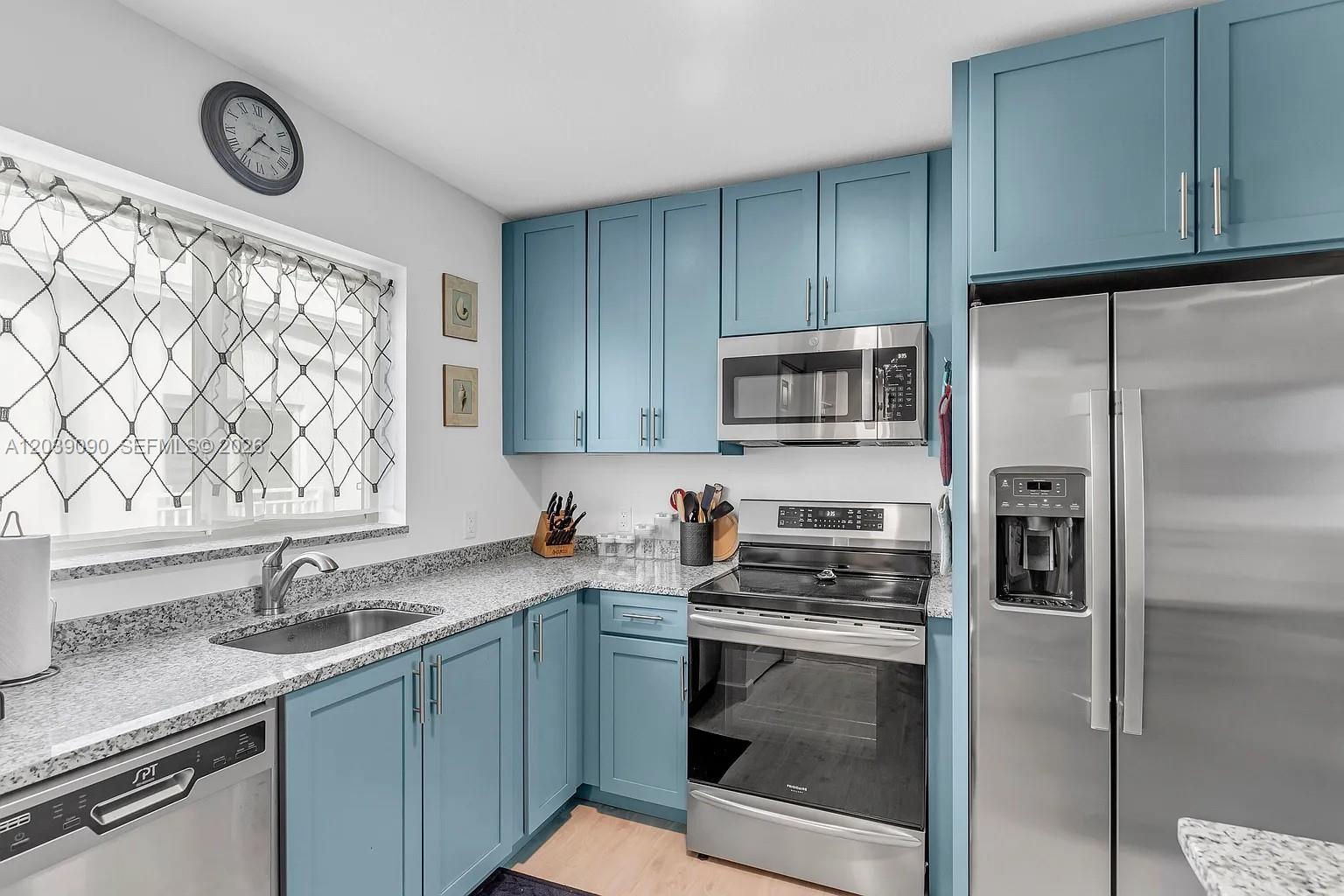 A kitchen features blue cabinets, stainless steel appliances, and granite countertops — 10877 Overseas Hwy # 37, Marathon FL 33050, MARATHON, FL