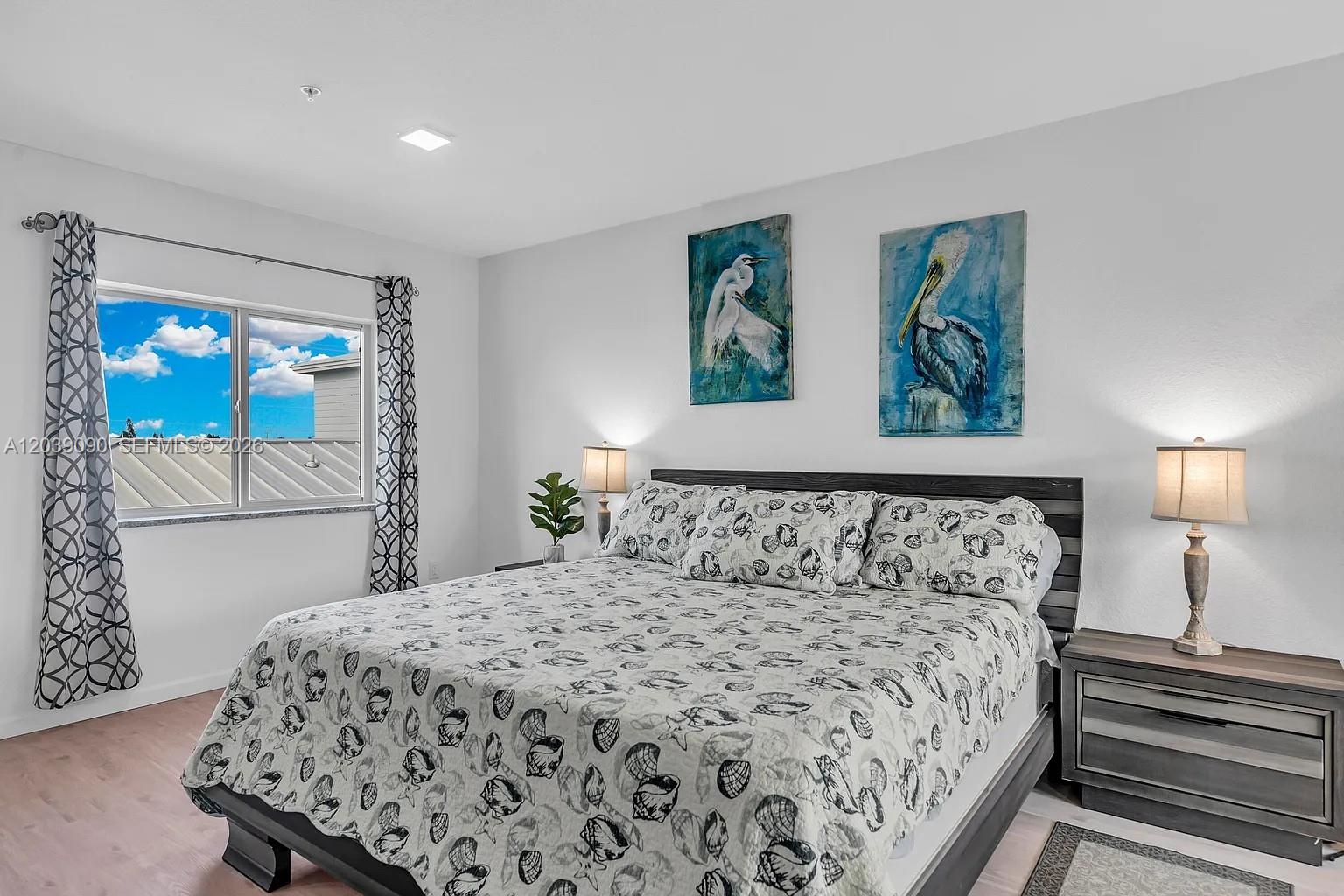 A bedroom features a bed with seashell-patterned bedding, two bird paintings, and matching bedside lamps — 10877 Overseas Hwy # 37, Marathon FL 33050, MARATHON, FL