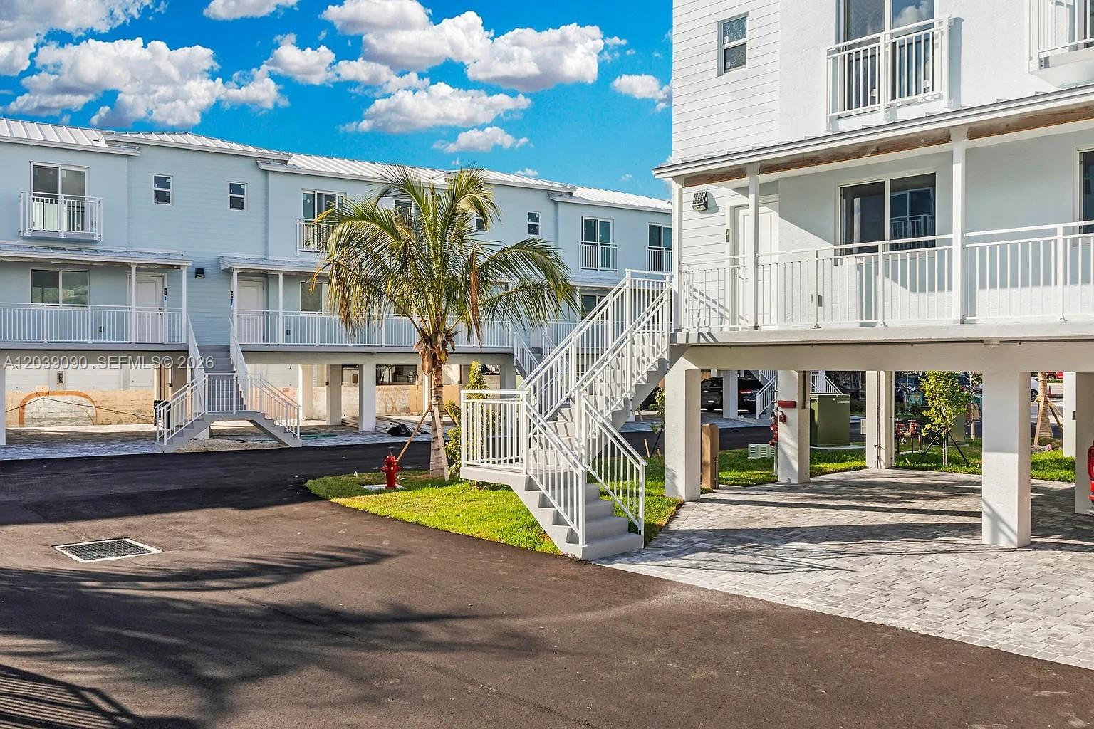 Exterior view of multi-story residential buildings with elevated balconies, white railings, and paved parking areas — 10877 Overseas Hwy # 37, Marathon FL 33050, MARATHON, FL
