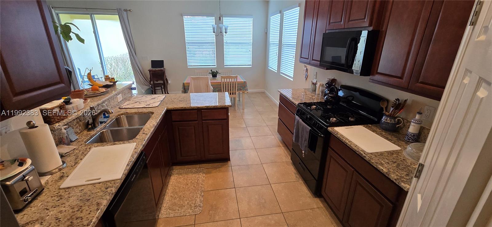 A kitchen features dark wood cabinets, granite countertops, stainless steel appliances, and a dining area — 1460 Caddy Ct, Vero Beach FL 32966, VERO BEACH, FL
