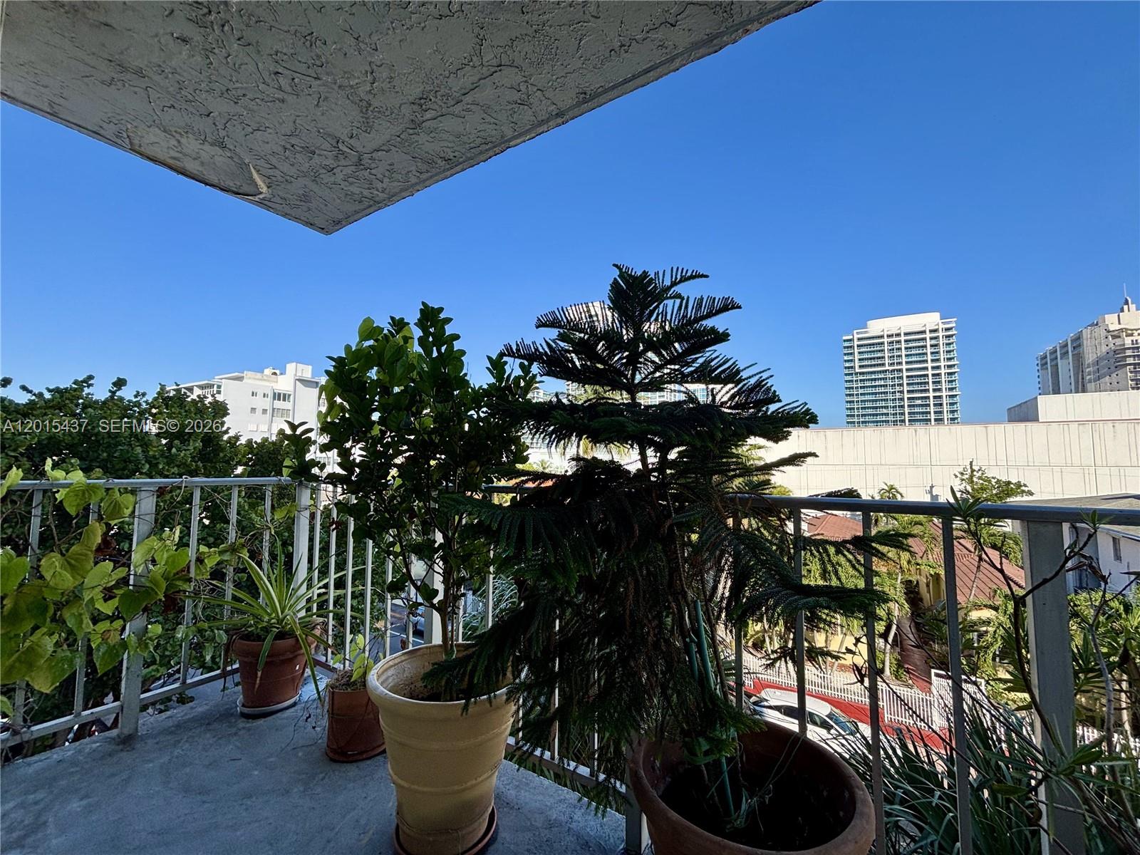 A balcony with potted plants overlooks a city street and high-rise buildings — 6801 Indian Creek Dr # 402, Miami Beach FL 33141, MIAMI BEACH, FL