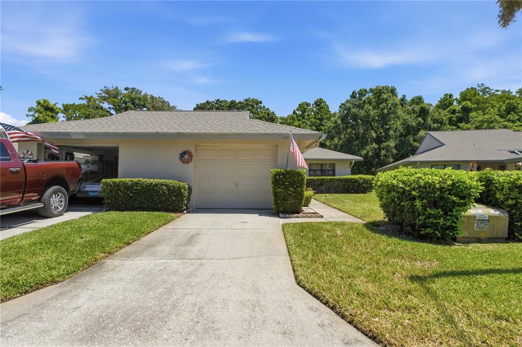 A single-story house with a beige garage, a concrete driveway, and green landscaping — 3249 LORI LANE UNIT 3249, NEW PORT RICHEY, FL