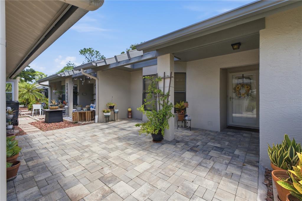 A paved courtyard leads to a covered entryway with a glass-paneled front door — 3249 LORI LANE UNIT 3249, NEW PORT RICHEY, FL