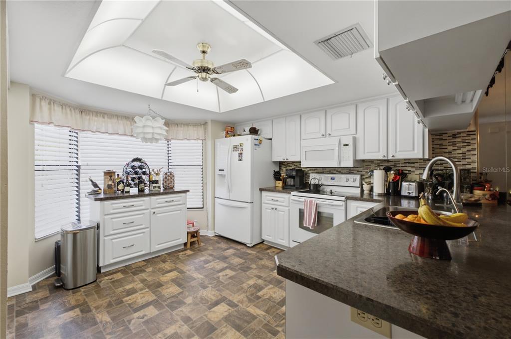 A kitchen with white cabinets, dark countertops, a ceiling fan, and tile flooring — 3249 LORI LANE UNIT 3249, NEW PORT RICHEY, FL