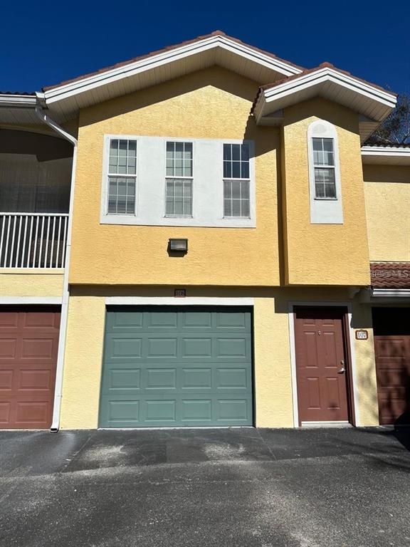 A two-story yellow stucco building features a green garage door and a brown front door — 12220 WILD IRIS WAY UNIT 108, ORLANDO, FL