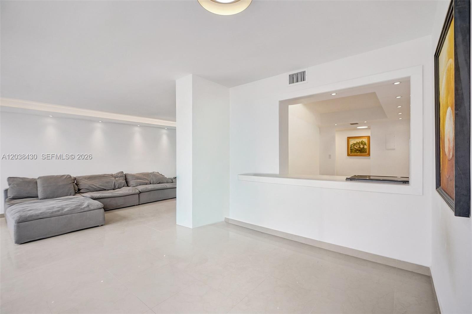 A living room with a grey sectional sofa and a pass-through window to the kitchen — 400 Leslie Dr # 1022, Hallandale Beach FL 33009, HALLANDALE BEACH, FL